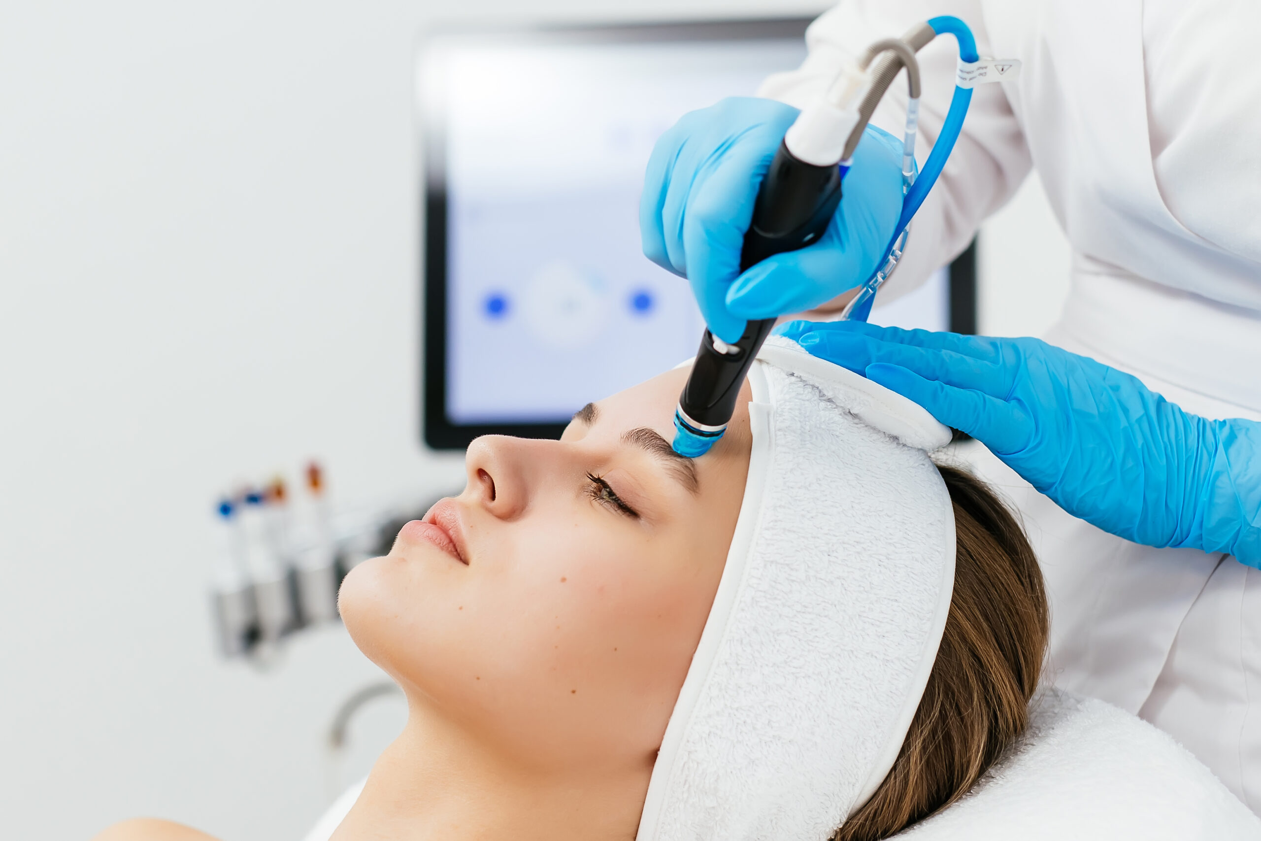 Close-up shot of a young beautiful woman lying on a couch in a cosmetology center. Young woman doing hydrofacial therapy in beauty spa.